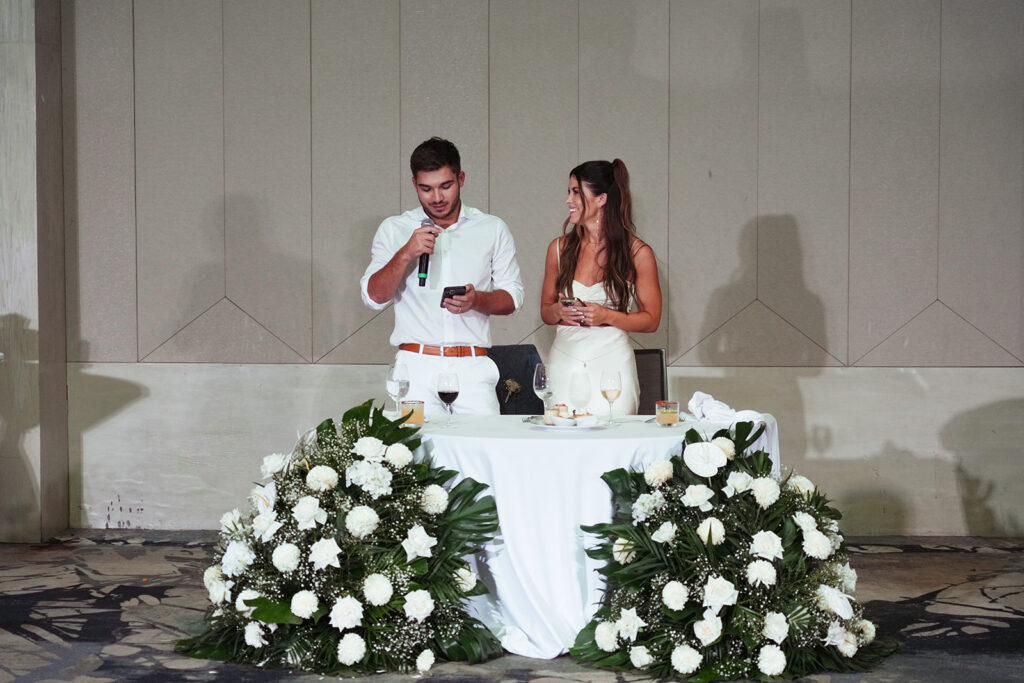 Bride and groom giving speech at sweetheart table during wedding reception at UNICO Hotel Riviera Maya