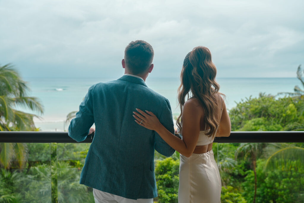 Bride and Groom standing on balcony looking out at ocean during First Look on wedding day at UNICO Hotel Riviera Maya