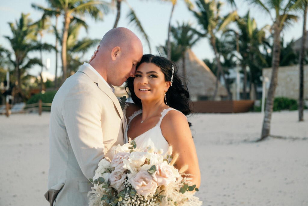bride and groom posing on beach with palm trees at hard rock punta cana resort 