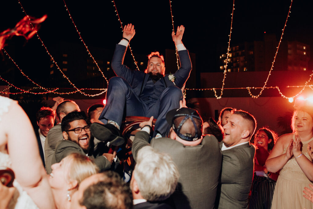 groom being tossed in the air on a chair during wedding reception