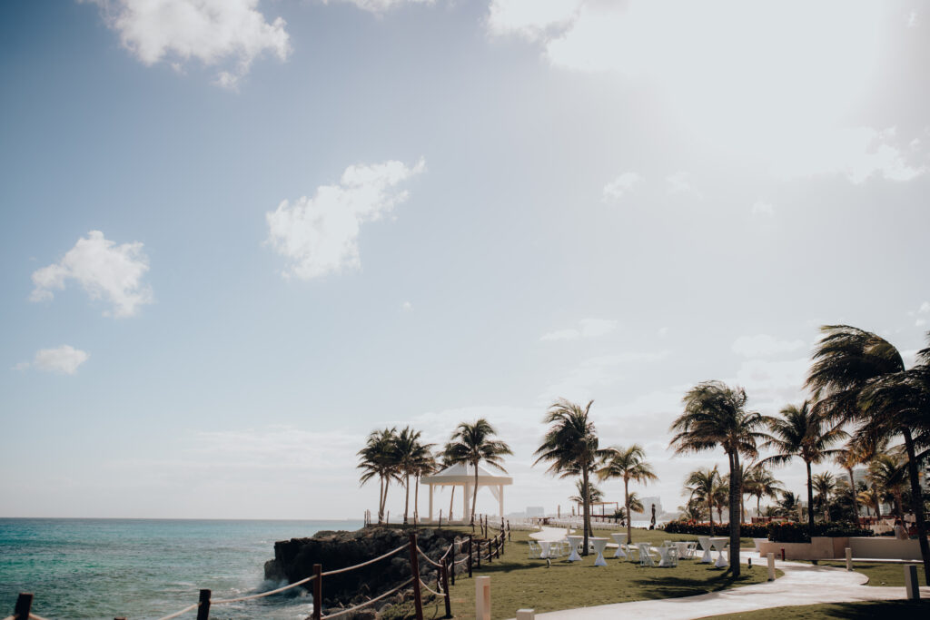 ceremony and cocktail hour space at hyatt ziva cancun with gazebo, high top tables, and palm trees alongside the ocean 