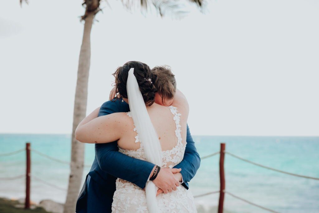 bride and groom hugging during first look with ocean in background 