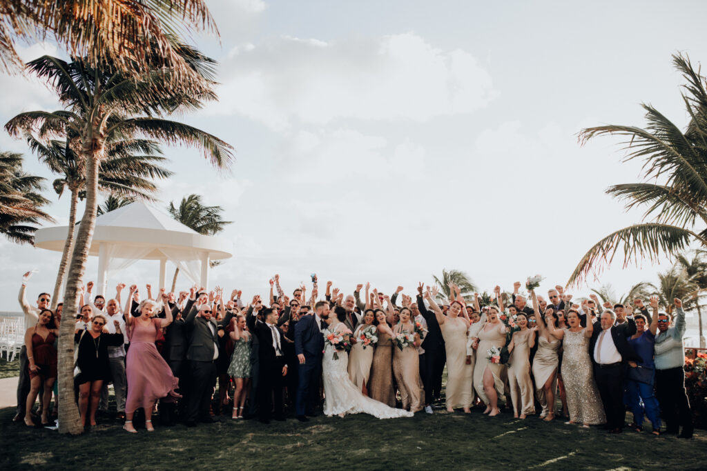 full wedding guest group photo under palm trees at hyatt ziva cancun