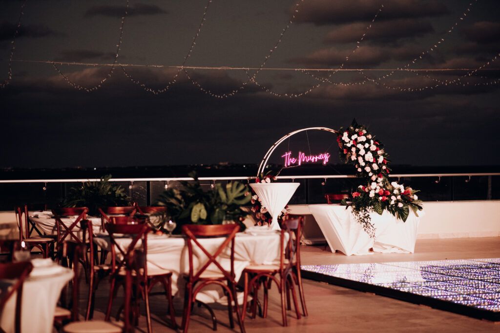 Rooftop wedding ceremony space at hyatt ziva cancun with light up dance floor and neon sign behind sweetheart table 