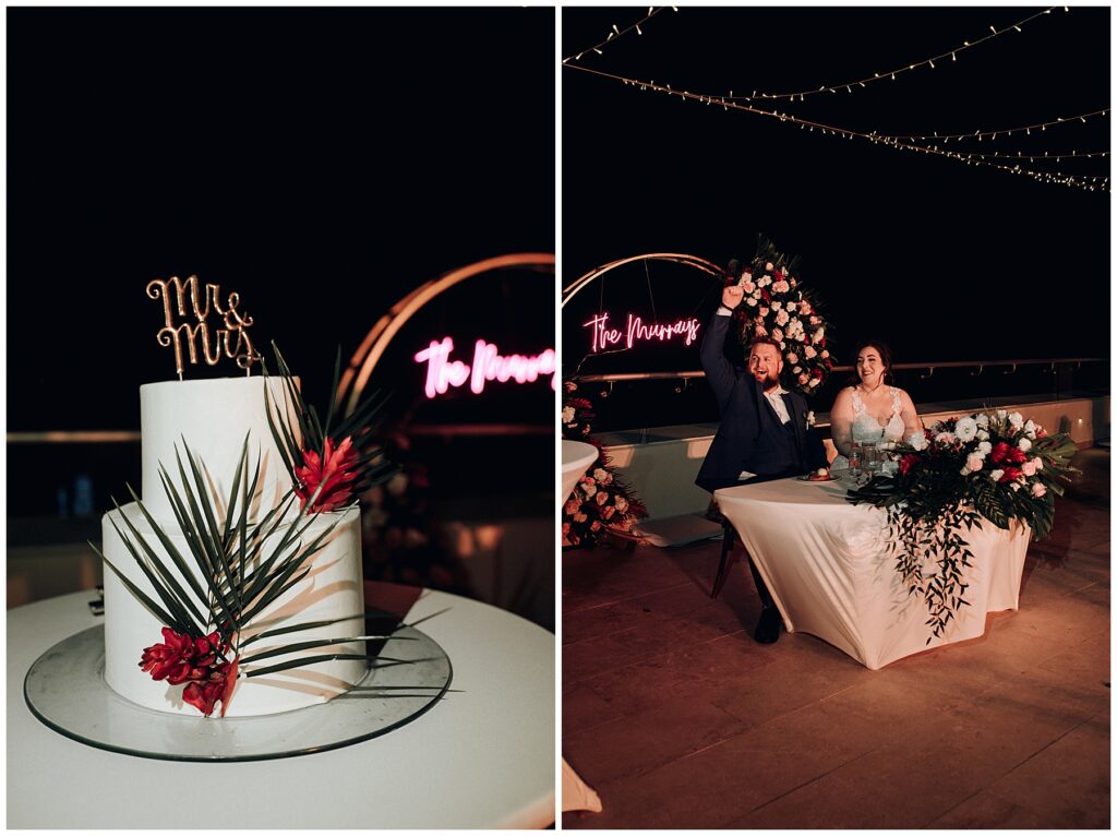 two tier white wedding cake with palm leaves and red flowers with gold "mr & mrs" cake topper